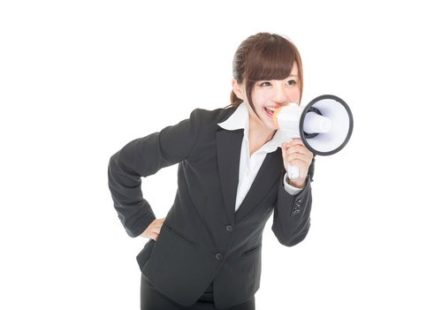 拡声器で大声を上げて応援する黒いスーツの女性社員