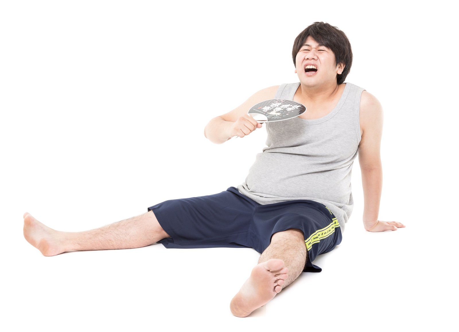 うちわであおぐ暑そうな男性が床に座っている［モデル：あまのじゃく］