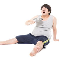 暑くてもぅダメ・・・うちわであおぐ男性の熱中症対策の写真