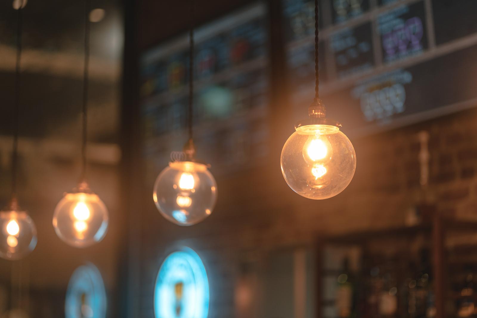 温かい光を放つ複数のペンダントライトがカフェの天井から吊り下げられている