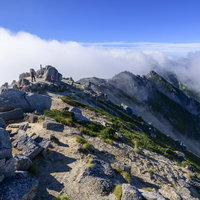 流れゆく雲の隙間から姿を現した中央アルプス空木岳の山頂の写真