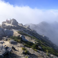 晴れた山頂に湧き上がる雲海と空木岳の登山者の写真