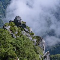 中央アルプス空木岳の石峰にかかる白い雲と緑の山肌の写真