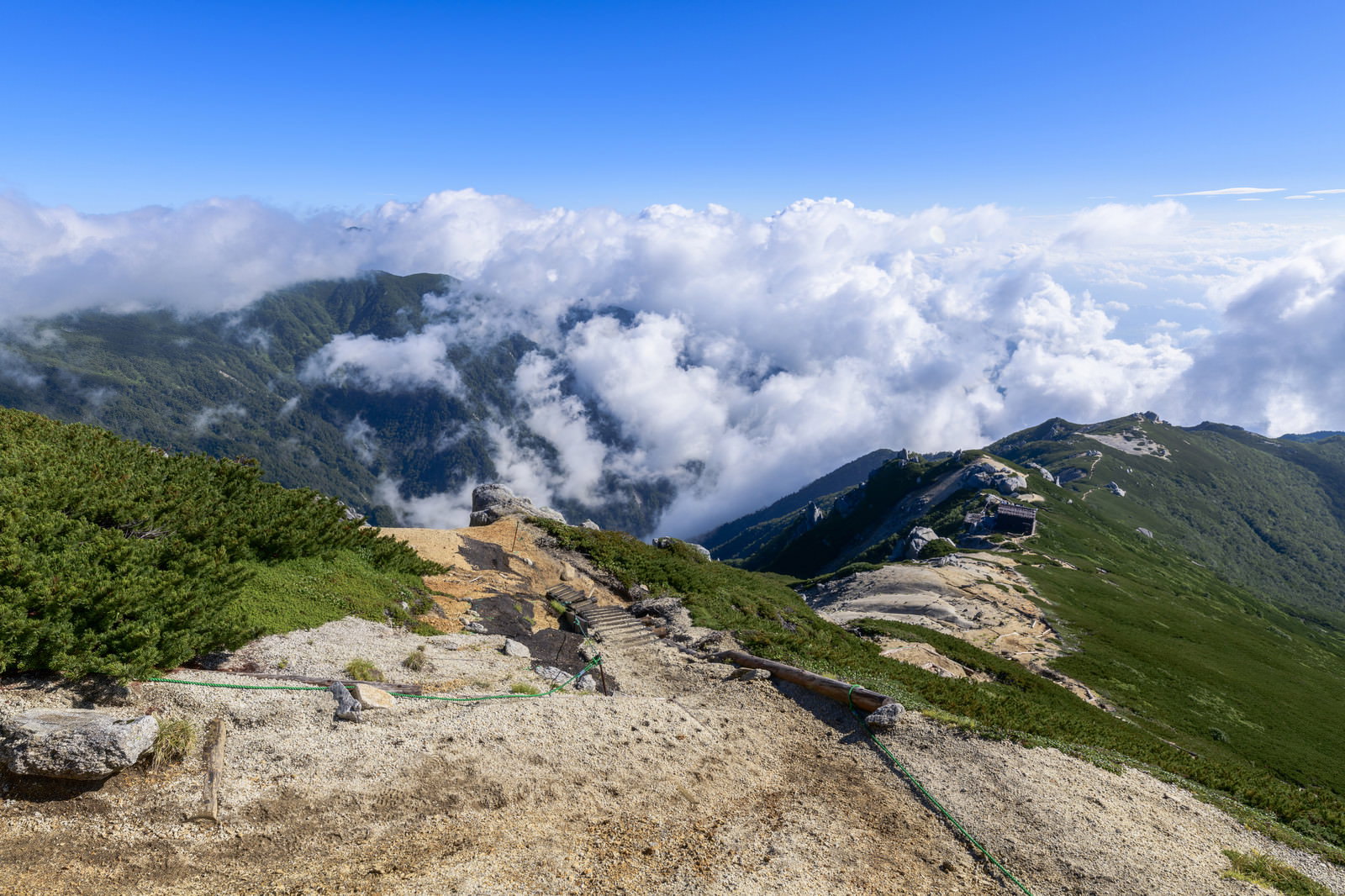 雲海に包まれた中央アルプスの稜線に建つ駒峰ヒュッテと周囲の山々
