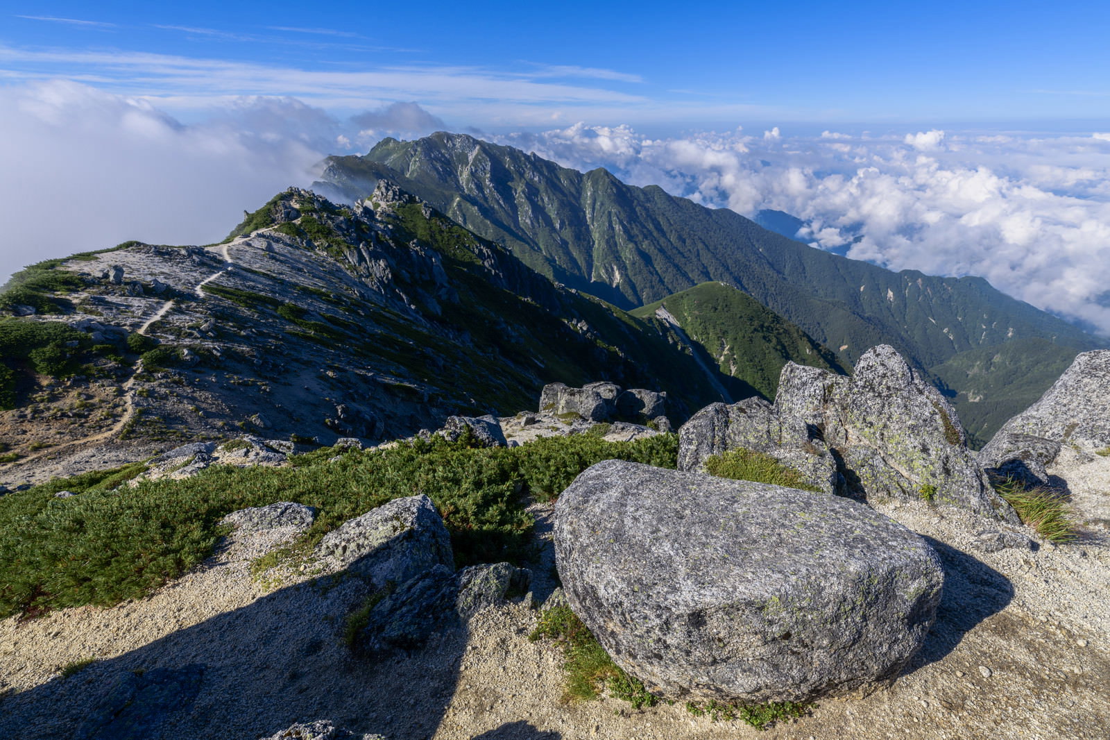 空木岳山頂の花崗岩と背景に見える南駒ヶ岳の山並み