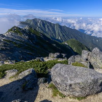 空木岳山頂に点在する花崗岩と南駒ヶ岳の山容の写真