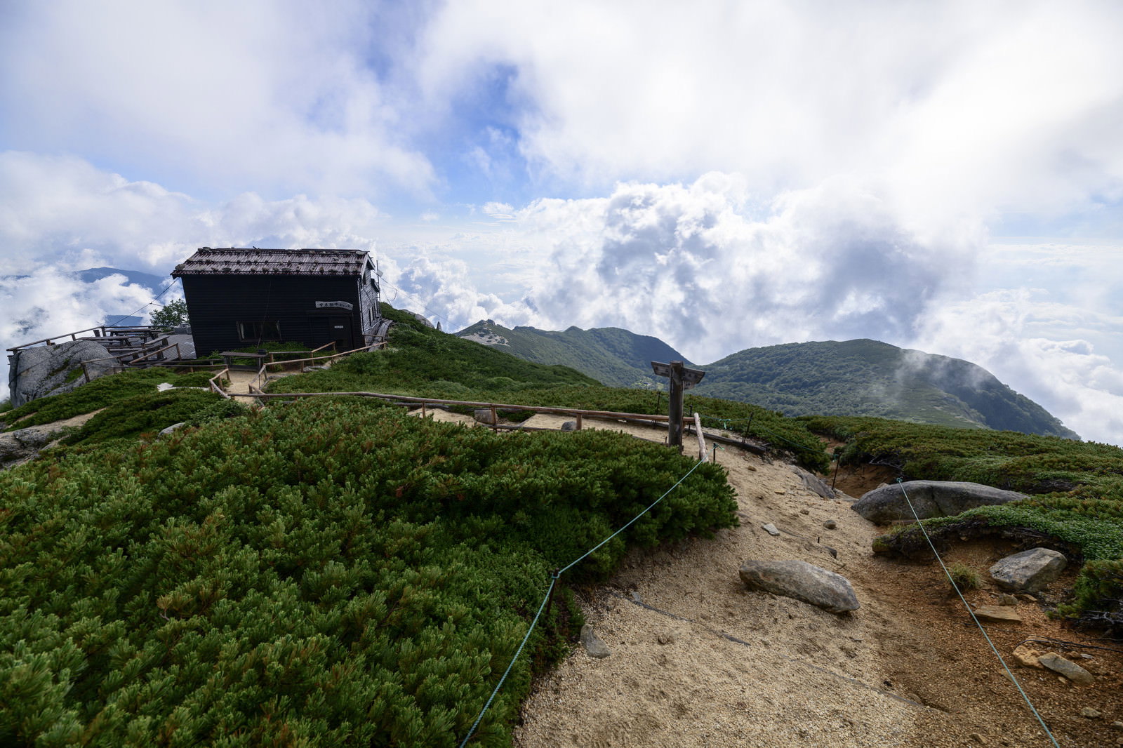 中央アルプス空木岳の稜線に建つ駒峰ヒュッテと青空に浮かぶ雲