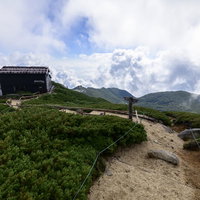 中央アルプス空木岳の稜線に建つ駒峰ヒュッテと雲の青空の写真