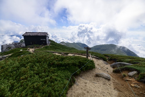 中央アルプス空木岳の稜線に建つ駒峰ヒュッテと雲の青空