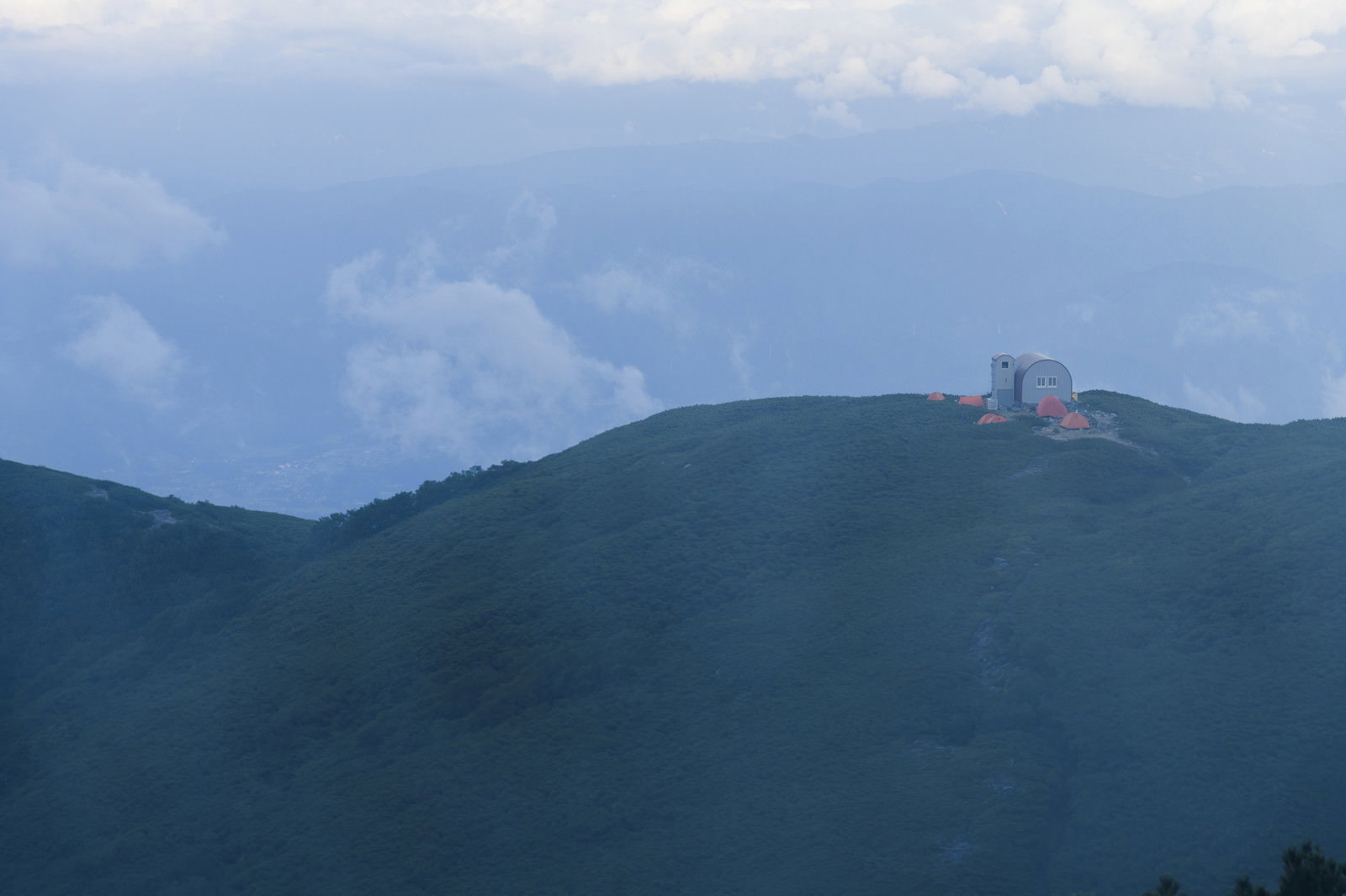 霧に包まれた中央アルプスの山稜に佇む檜尾岳の避難小屋