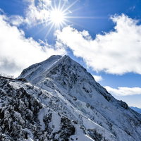 太陽をその頭に抱く雪の赤岳、八ヶ岳連峰の冬景色の写真