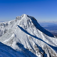 快晴の空の元、雪化粧した日本百名山の阿弥陀岳の写真