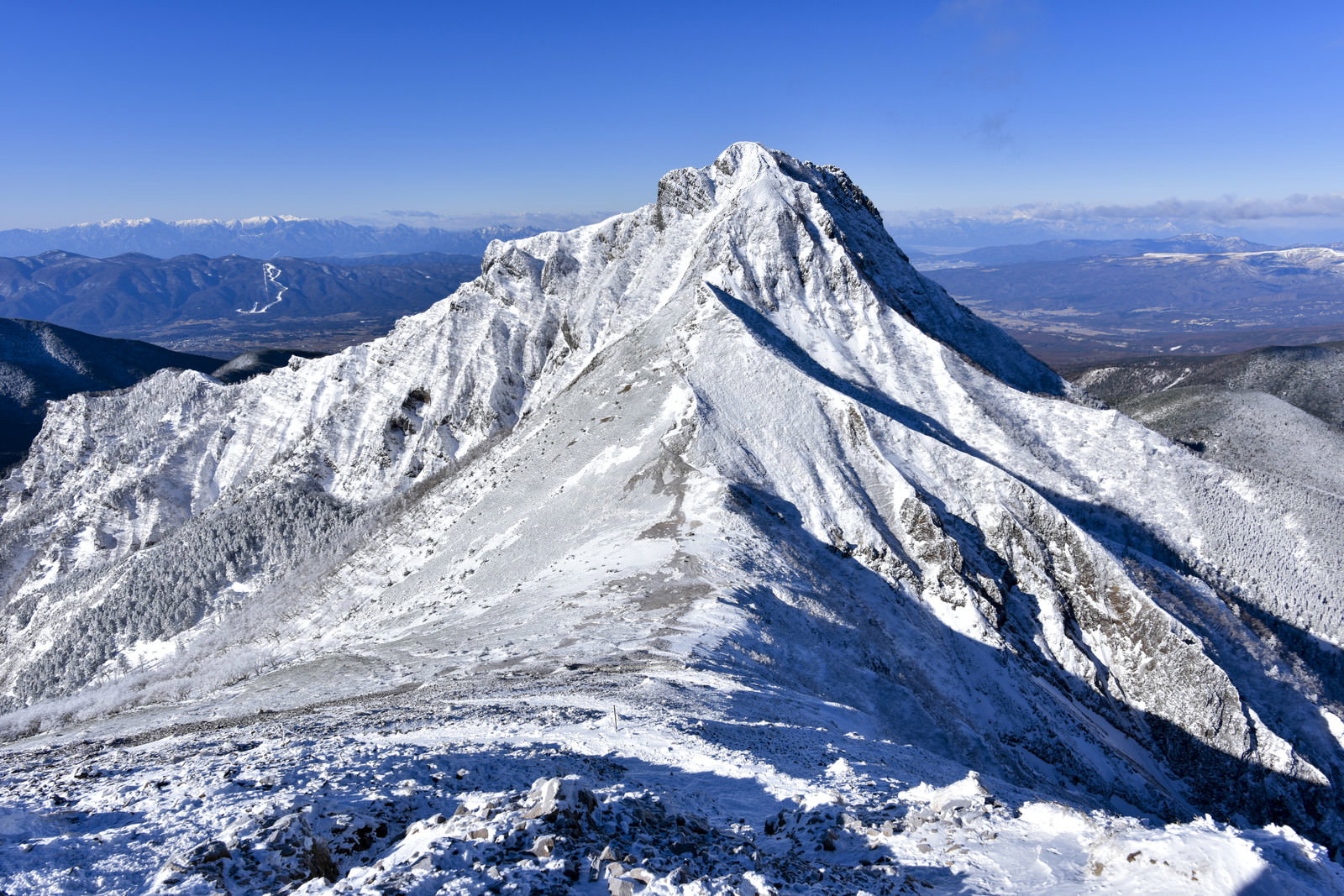 雪に覆われた阿弥陀岳の山頂と青空が広がる八ヶ岳連峰の景色