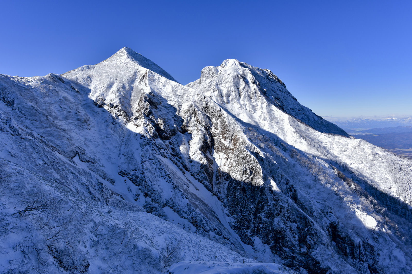 A winter landscape depicting the snow-clad Mount Amida and Mount Chūbetsu, photographed from the Bunzaburō Ridge.