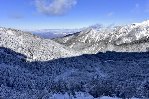 赤岳の影が重なる八ヶ岳連峰の雪の森と冬山の景観
