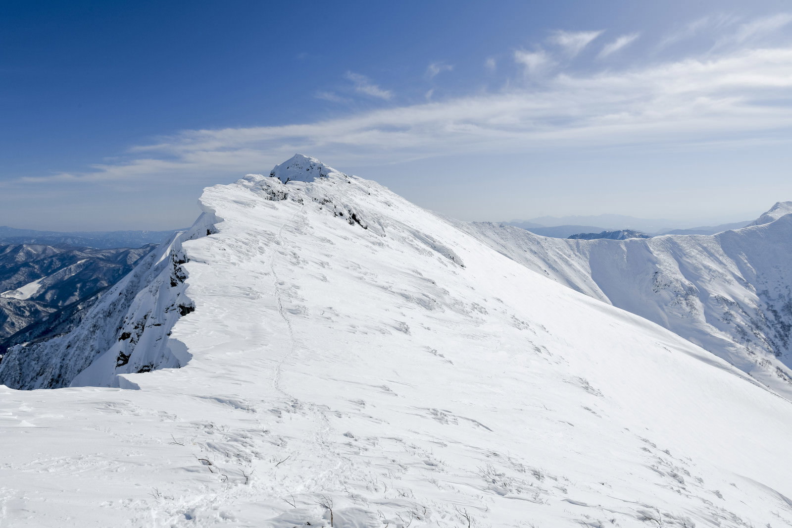 雪に覆われた一ノ倉岳から谷川岳へ続く登山道と青空