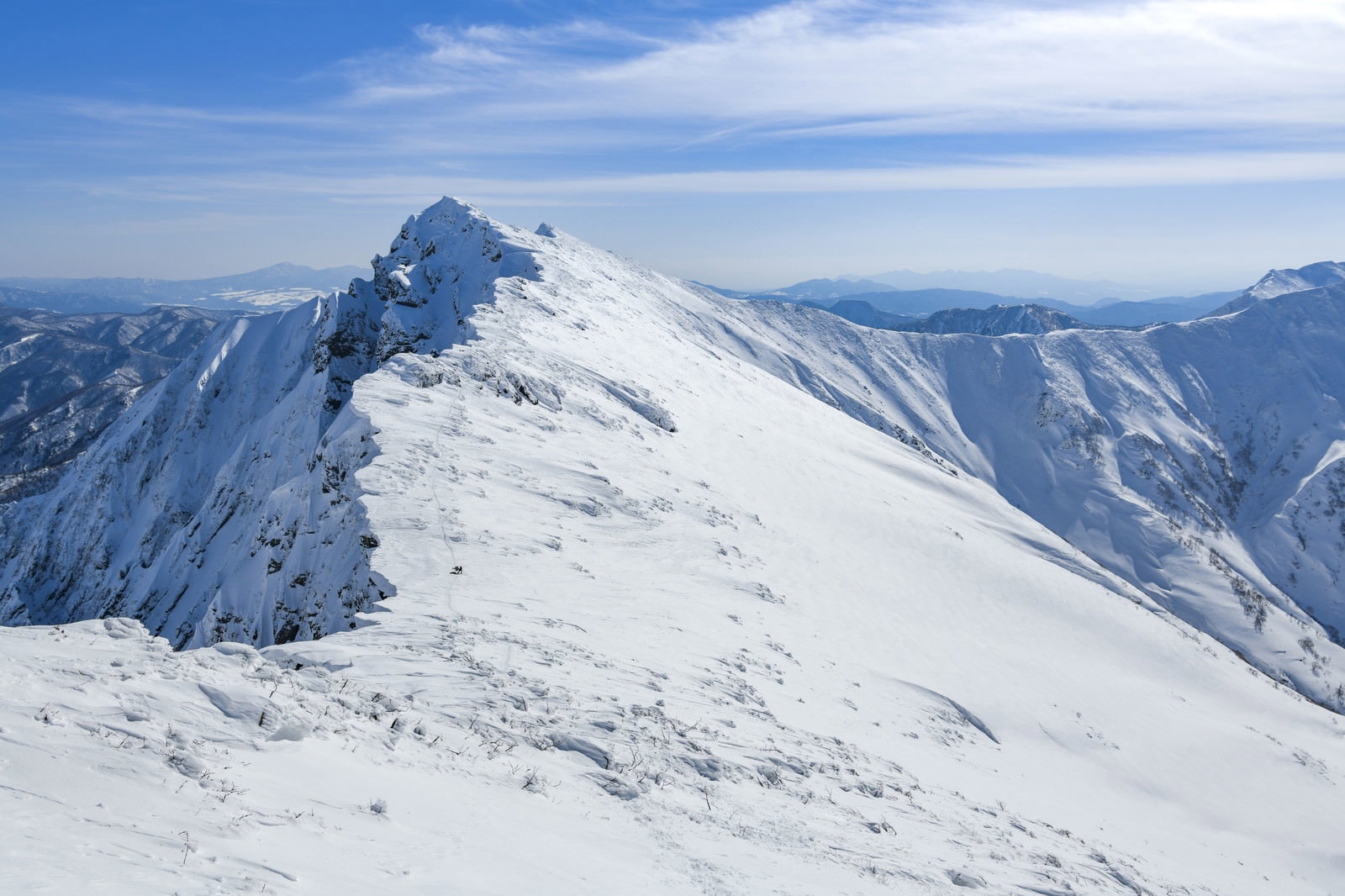 青空の下、雪に覆われた谷川岳の山頂を一ノ倉岳から撮影した山岳風景