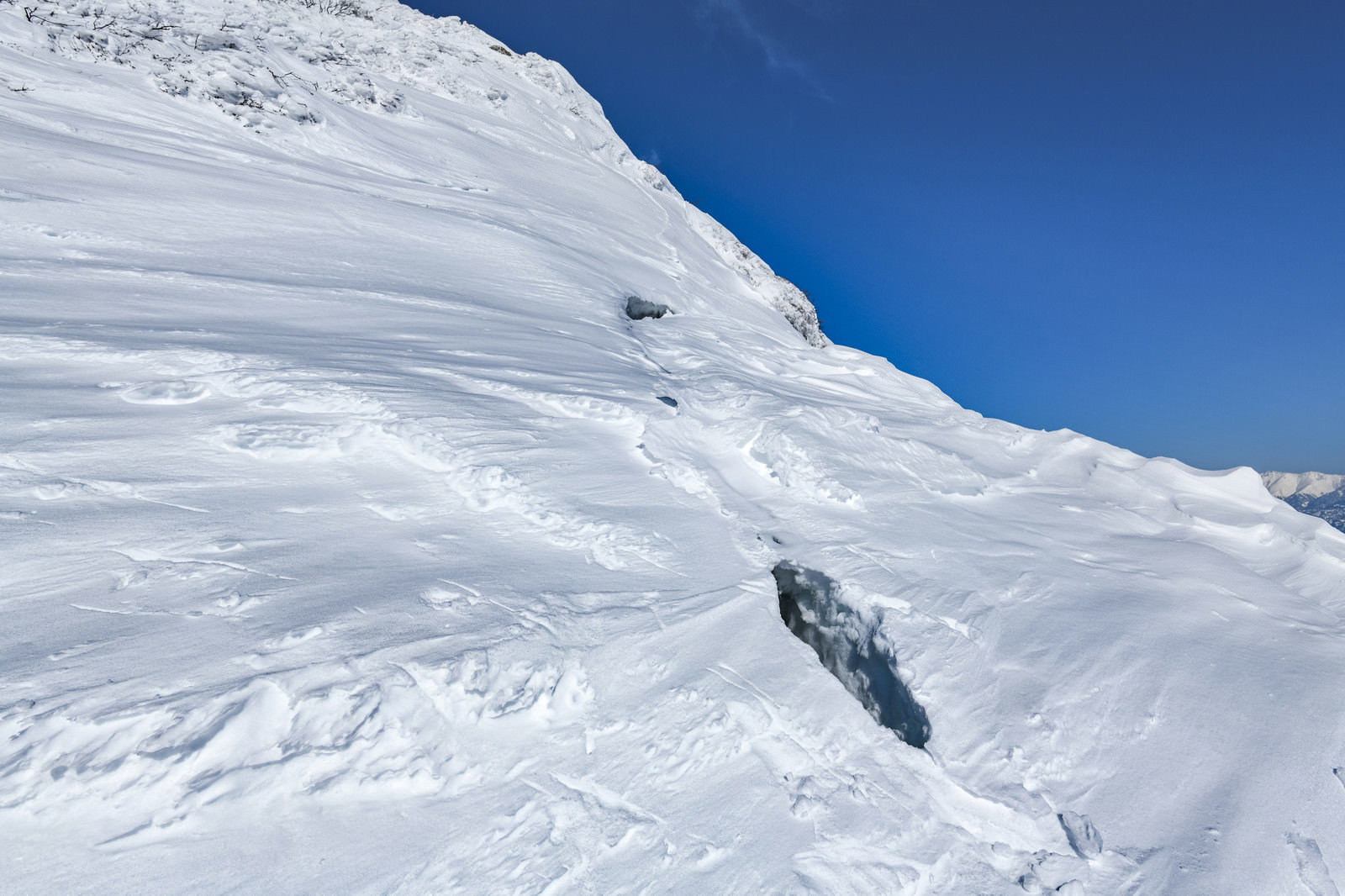 青空の下、谷川岳の稜線に張り出した大きな雪庇