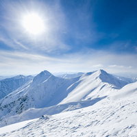 午後の日差しが照り付ける谷川岳主脈の雪山の写真