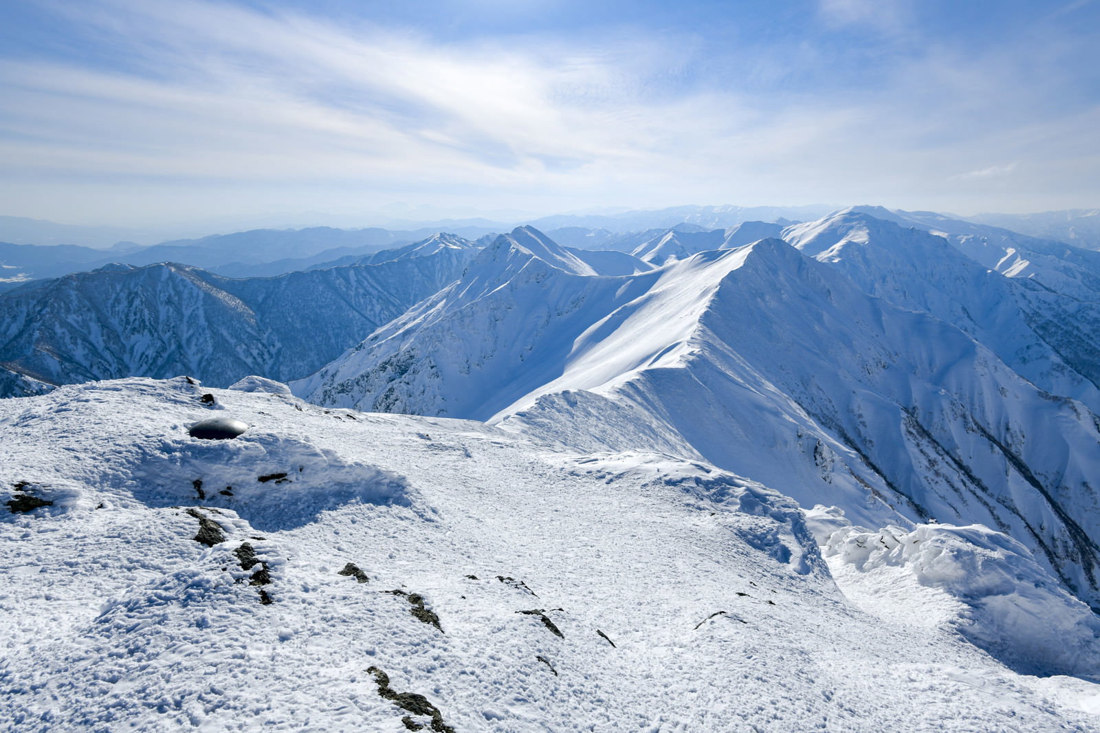雪に覆われた谷川岳主脈の稜線が青空の下に連なる風景