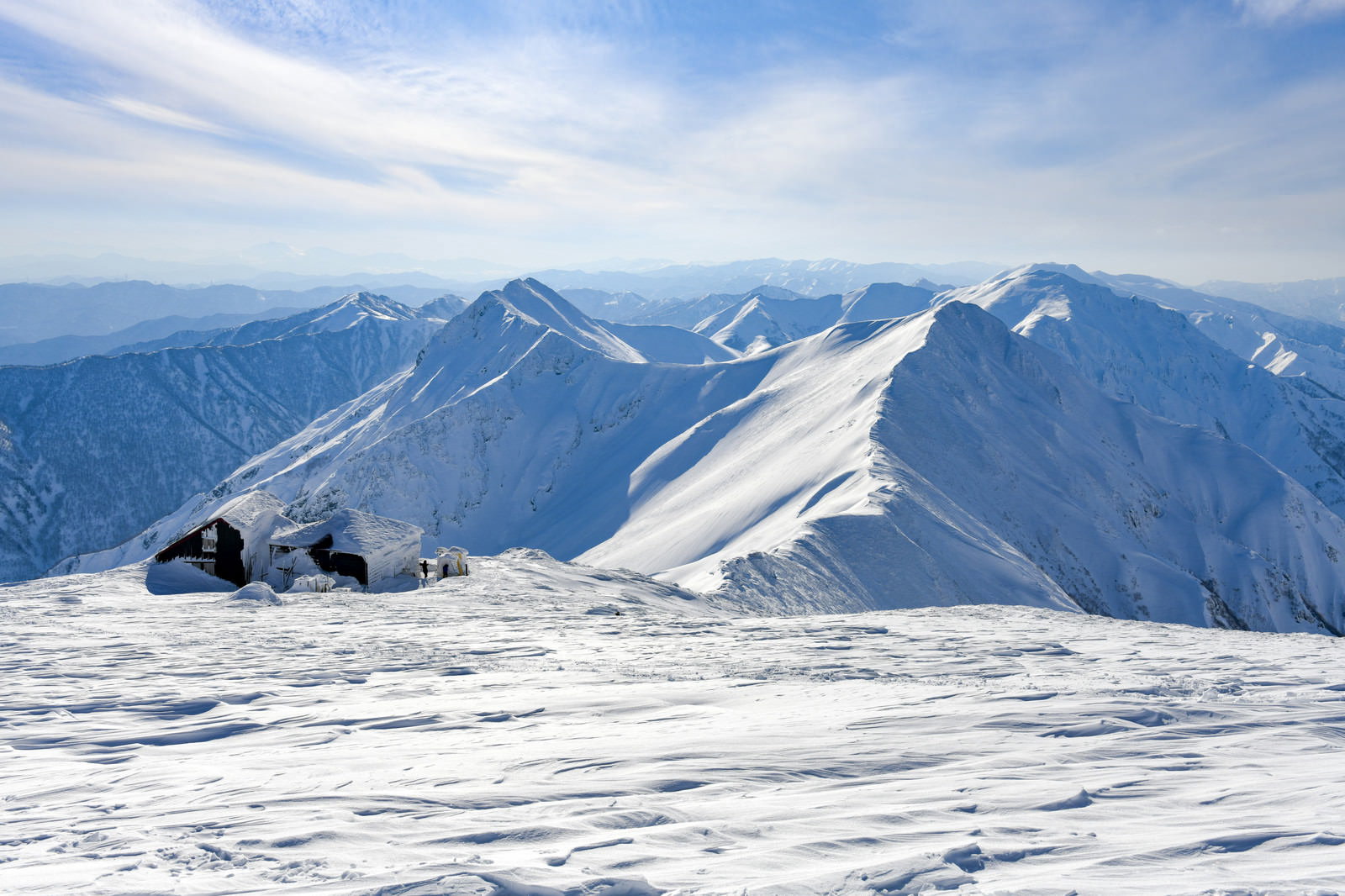 雪に覆われた谷川岳の山頂付近に建つ山小屋と雪山の風景
