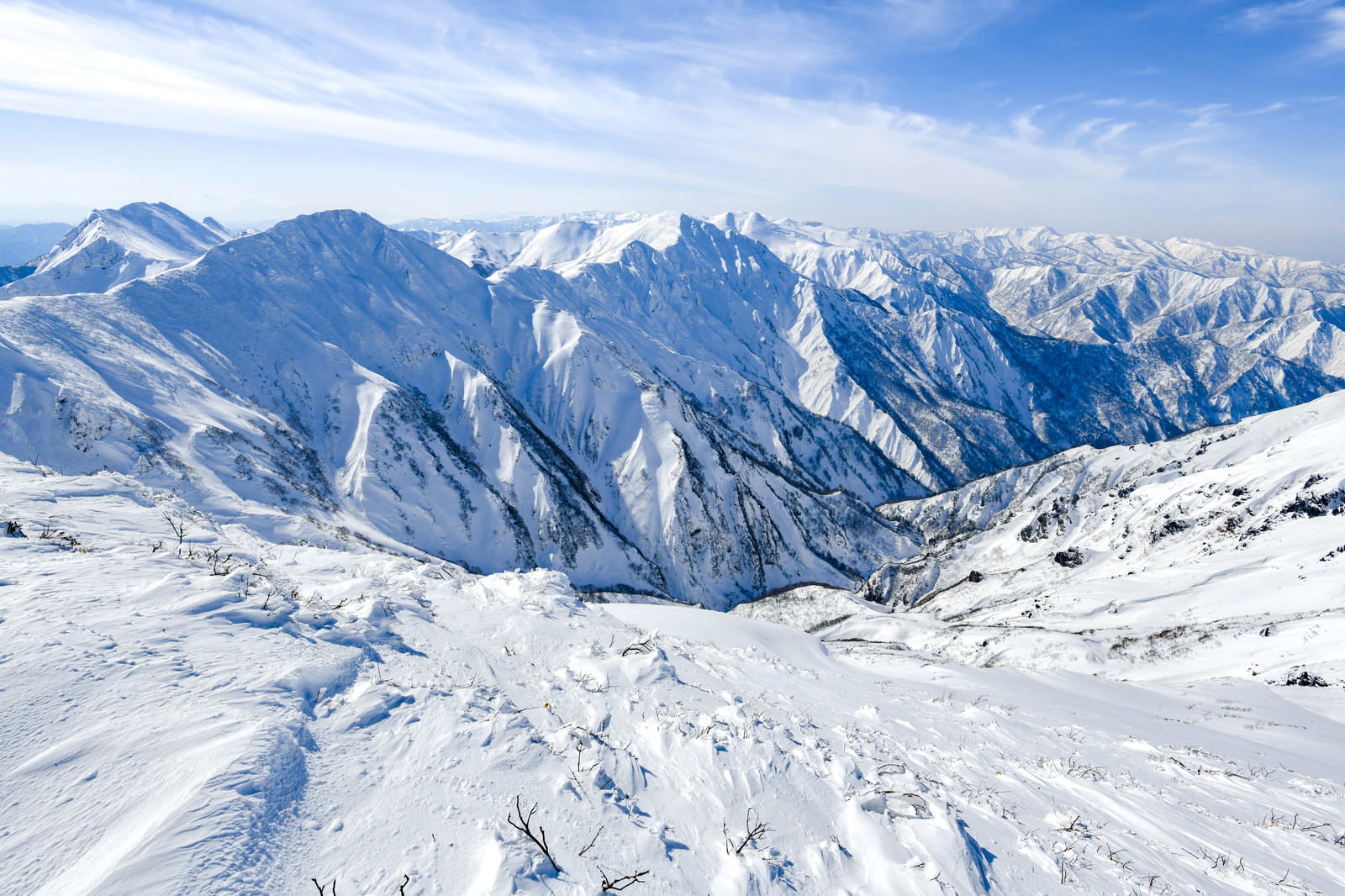 雪に覆われた谷川岳の山々と青空、手前にスキー場のゲレンデ