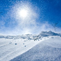 強風で湧き上がる雪煙と太陽（谷川岳）の写真