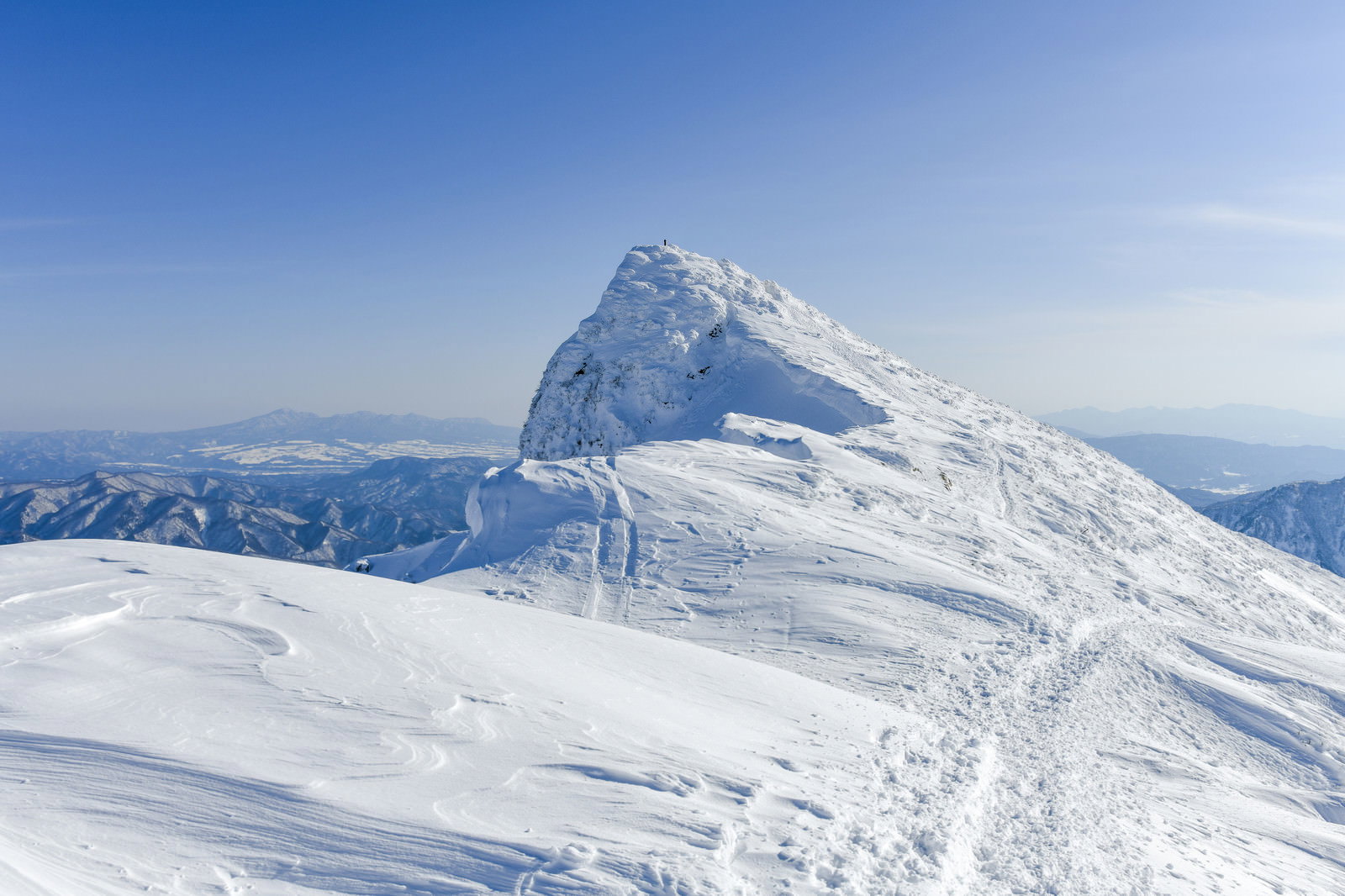 雪に覆われた谷川岳の山頂と青空の風景