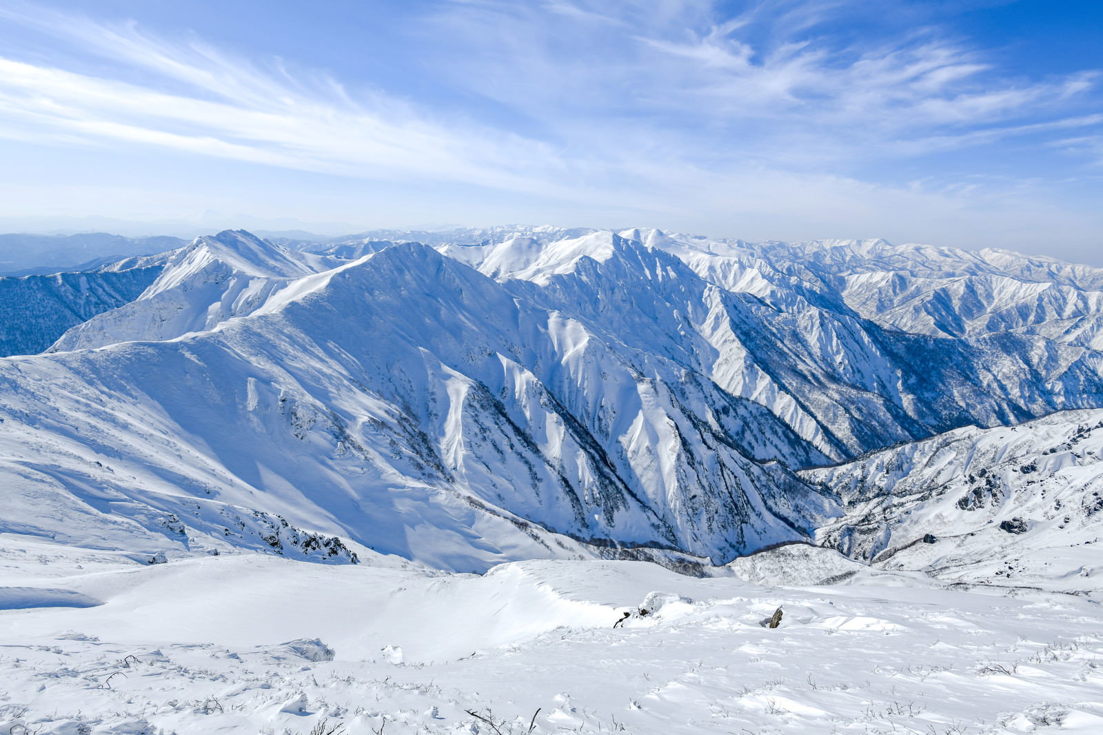 雪に覆われた谷川岳の山々と青空が広がる冬の山岳風景