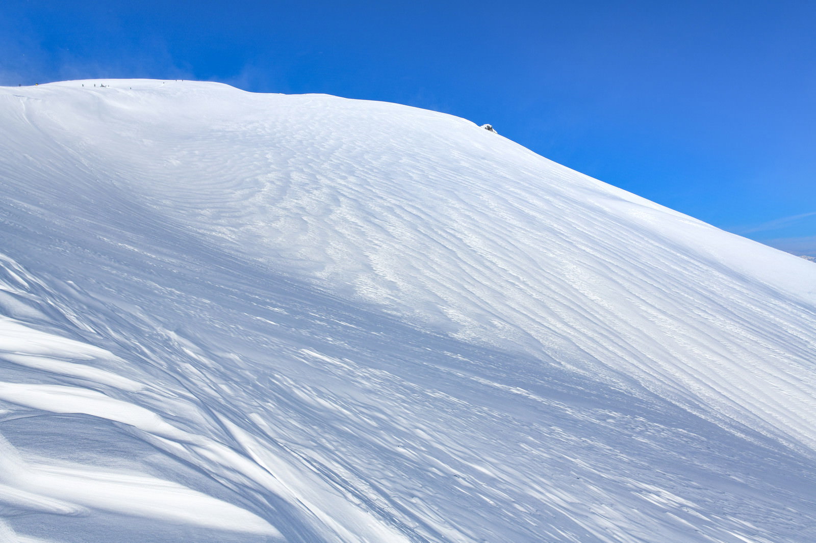 青空の下に白い雪で覆われた谷川岳の斜面が広がる風景