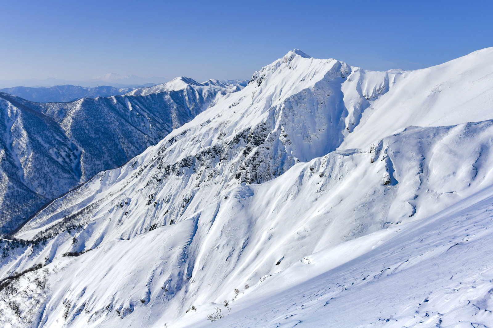 雪に覆われた川棚ノ頭の山々と青空が広がる谷川岳の冬景色
