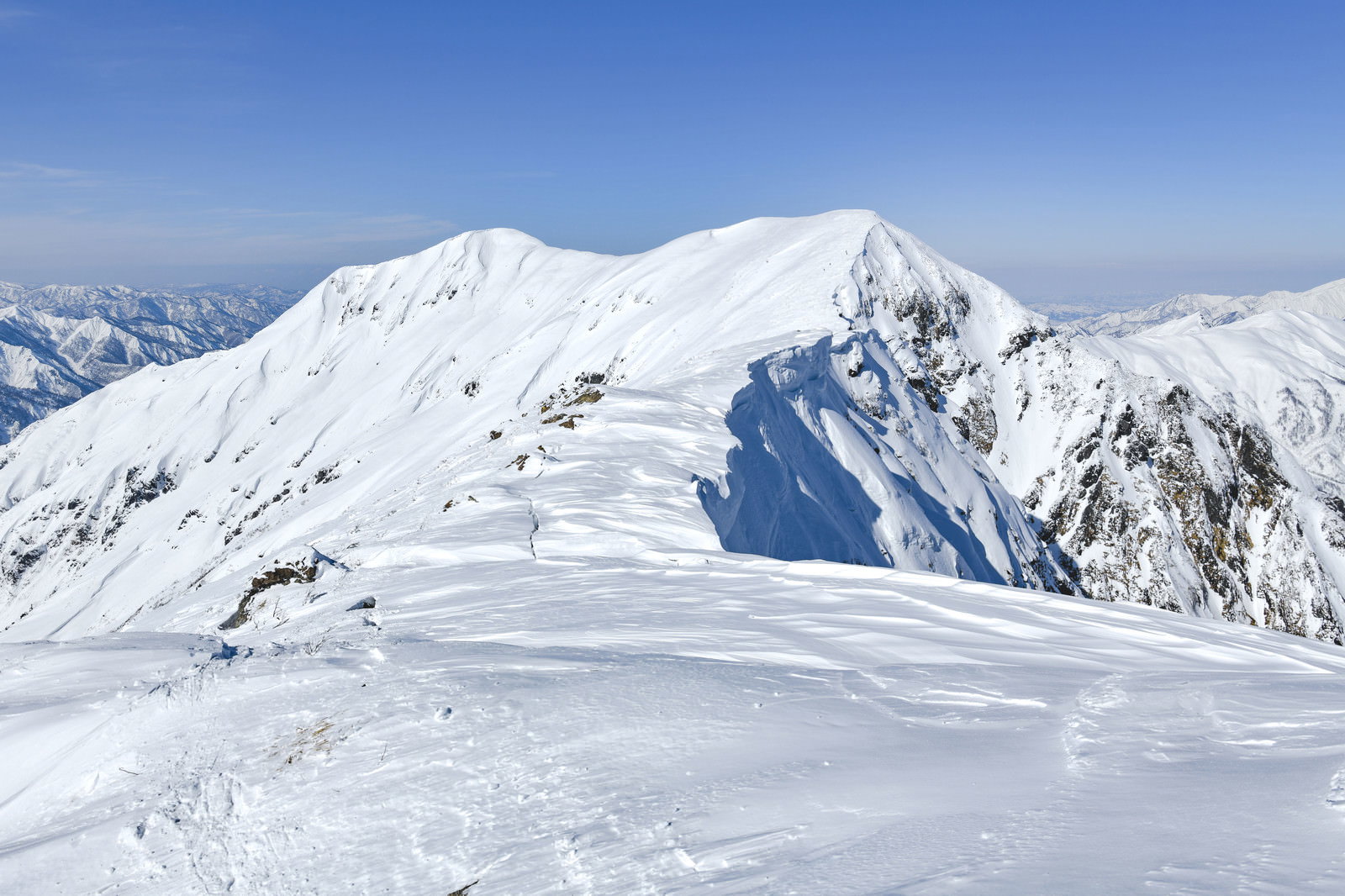 谷川岳から一ノ倉岳へと続く雪化粧した稜線と青空