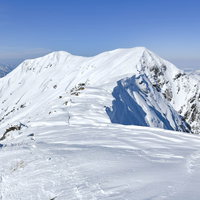 谷川岳から一ノ倉岳へと続く雪に覆われた稜線の写真