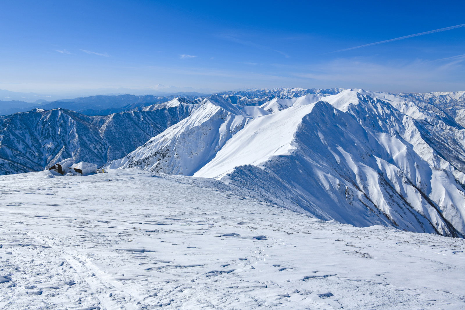 青空の下に雪化粧した谷川岳の山脈が連なる雪景色