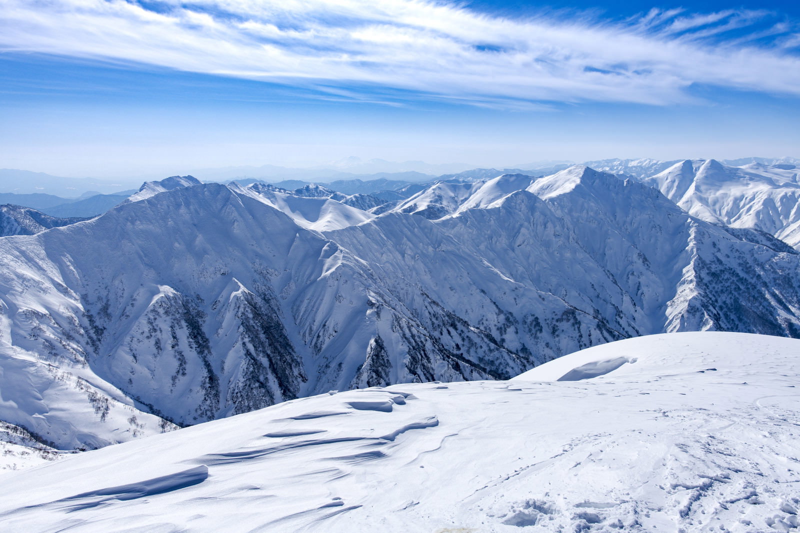 青空の下に広がる雪化粧した谷川岳の山脈と白い雪原