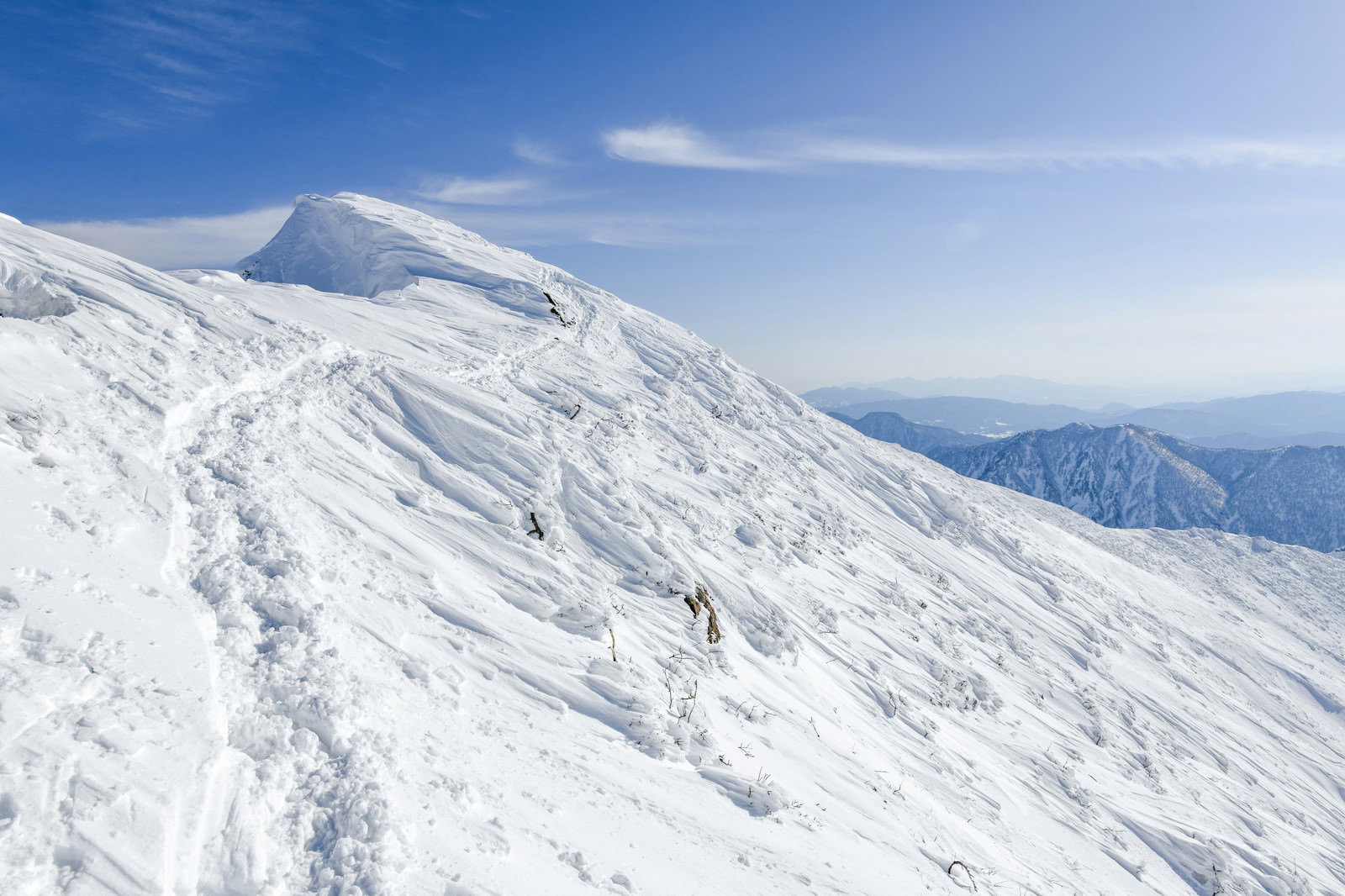 谷川岳の雪庇が発達した斜面を通る登山道と青空