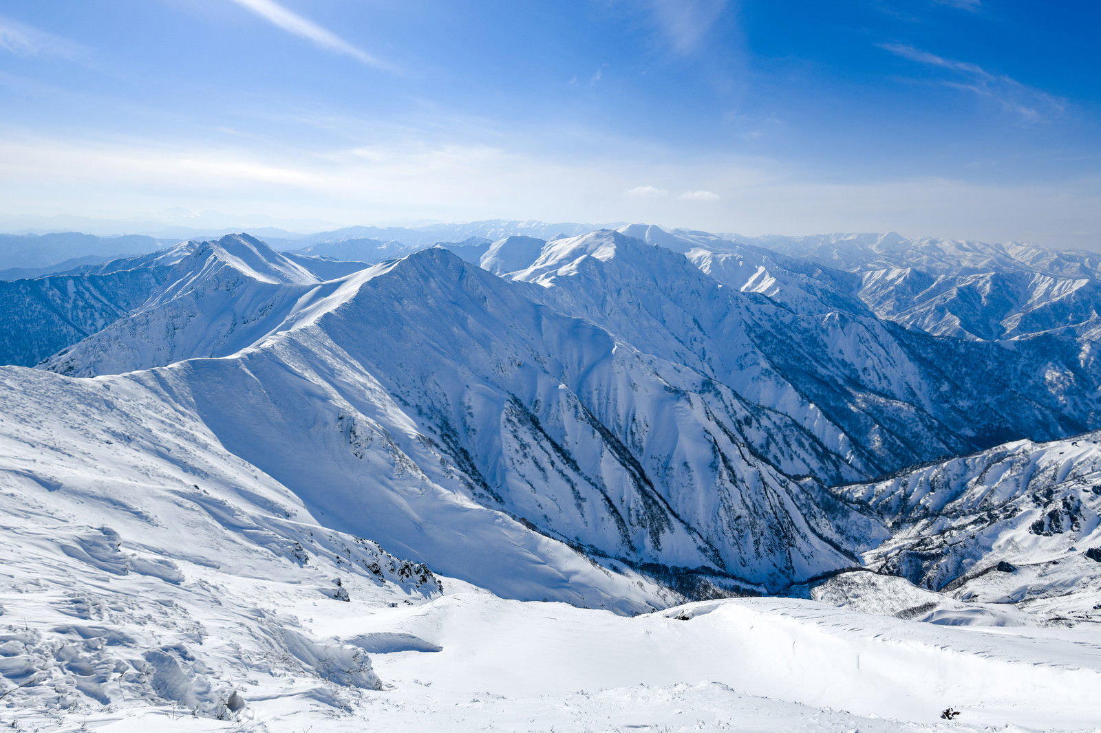 青空の下、雪に覆われた谷川岳の山稜が連なる冬の雪景色
