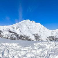 青空の元で真っ白に雪化粧した谷川岳の雪山風景の写真