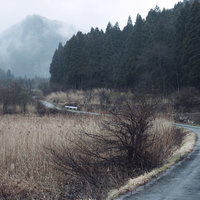 面白山高原へと続く舗装林道と霞む山々の風景の写真