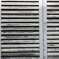 経年劣化で白いペンキが剥げた古い雨戸のクローズアップの写真