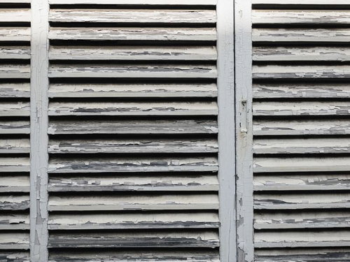 経年劣化で白いペンキが剥げた古い雨戸のクローズアップ