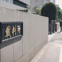 裁判所前の銘板と歩道 石材壁面の黒い看板と街並みの写真