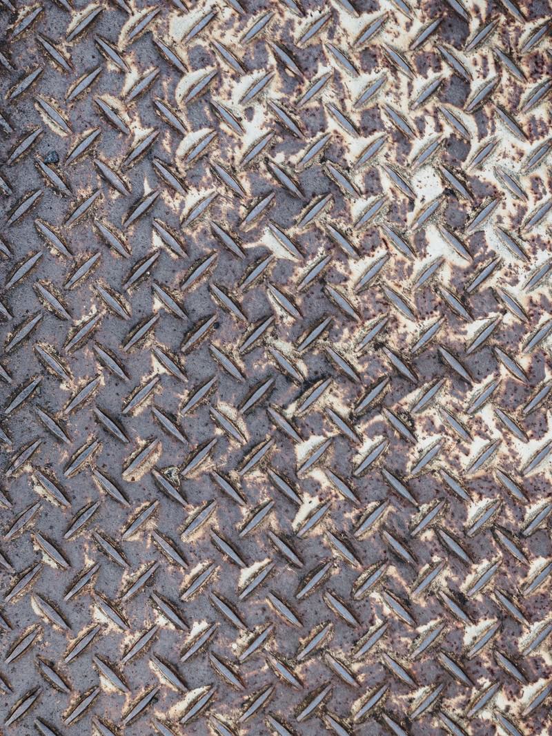 錆びた足場板の表面に滑り止めの縞模様が刻まれたテクスチャー