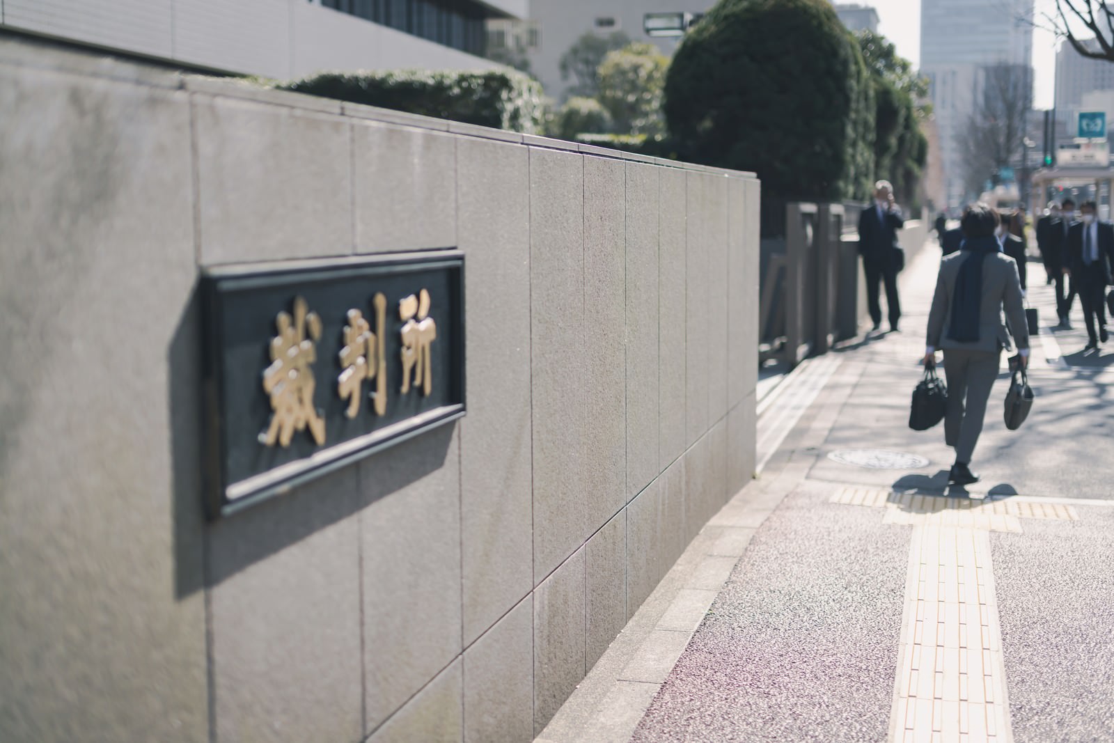 裁判所前の歩道に設置された銘板とその前を歩く人々