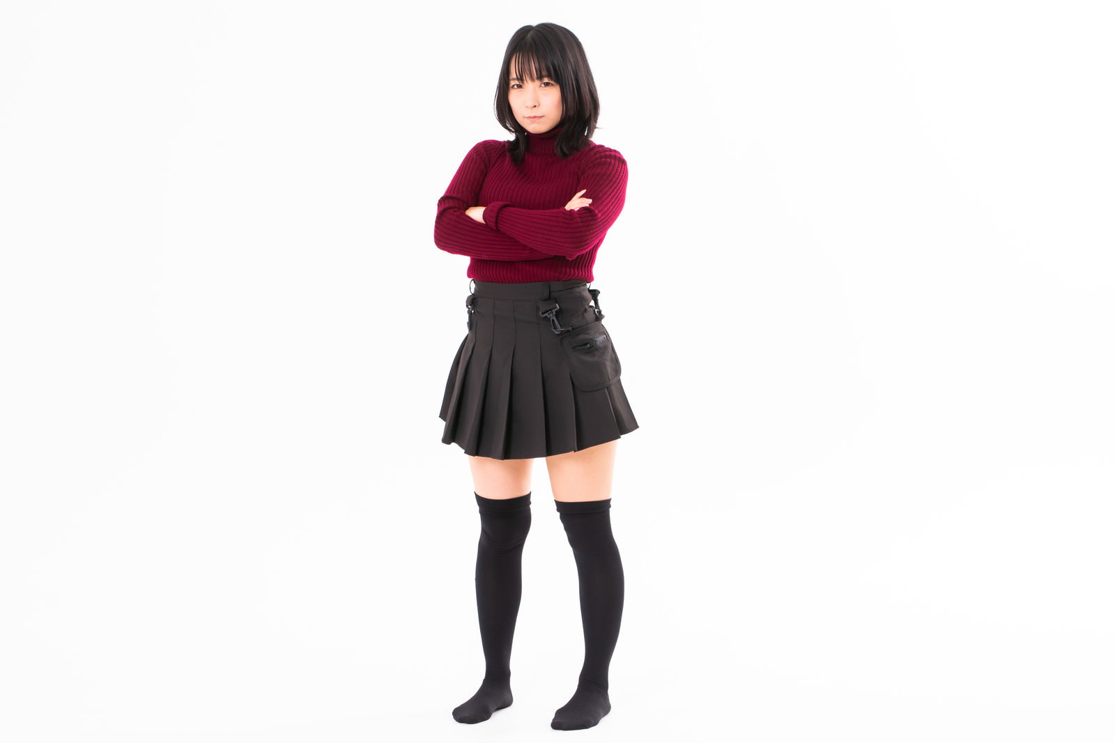 赤いトップスを着て腕組みをして怒った表情の女性［モデル：にゃるる］