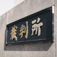 裁判所銘板と影が映る壁面の写真