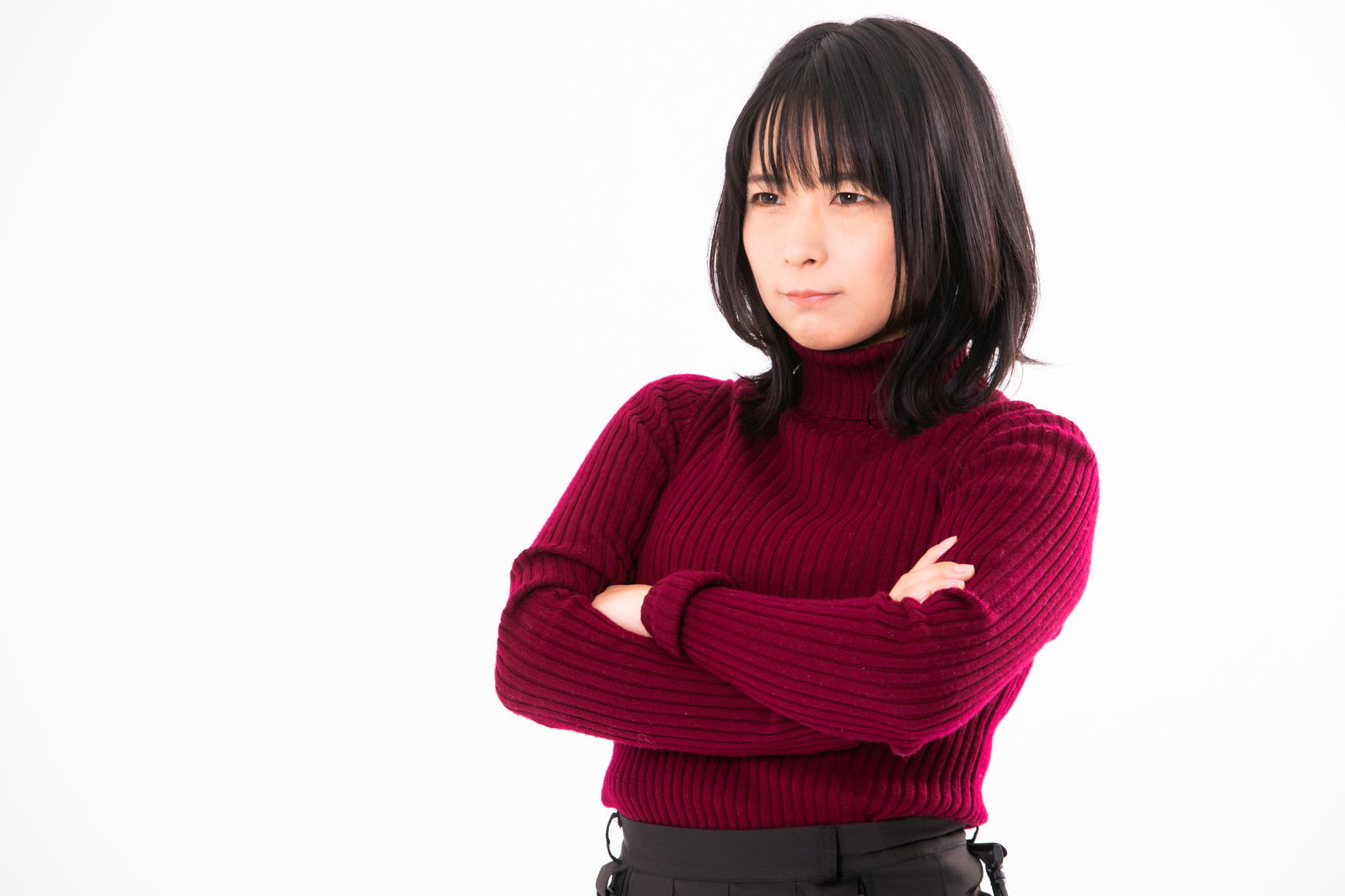 赤いセーターを着て腕を組み、不機嫌そうな表情を見せる女性［モデル：にゃるる］