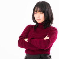 赤いセーターを着て腕を組み断固として許さない姿勢の女性の写真
