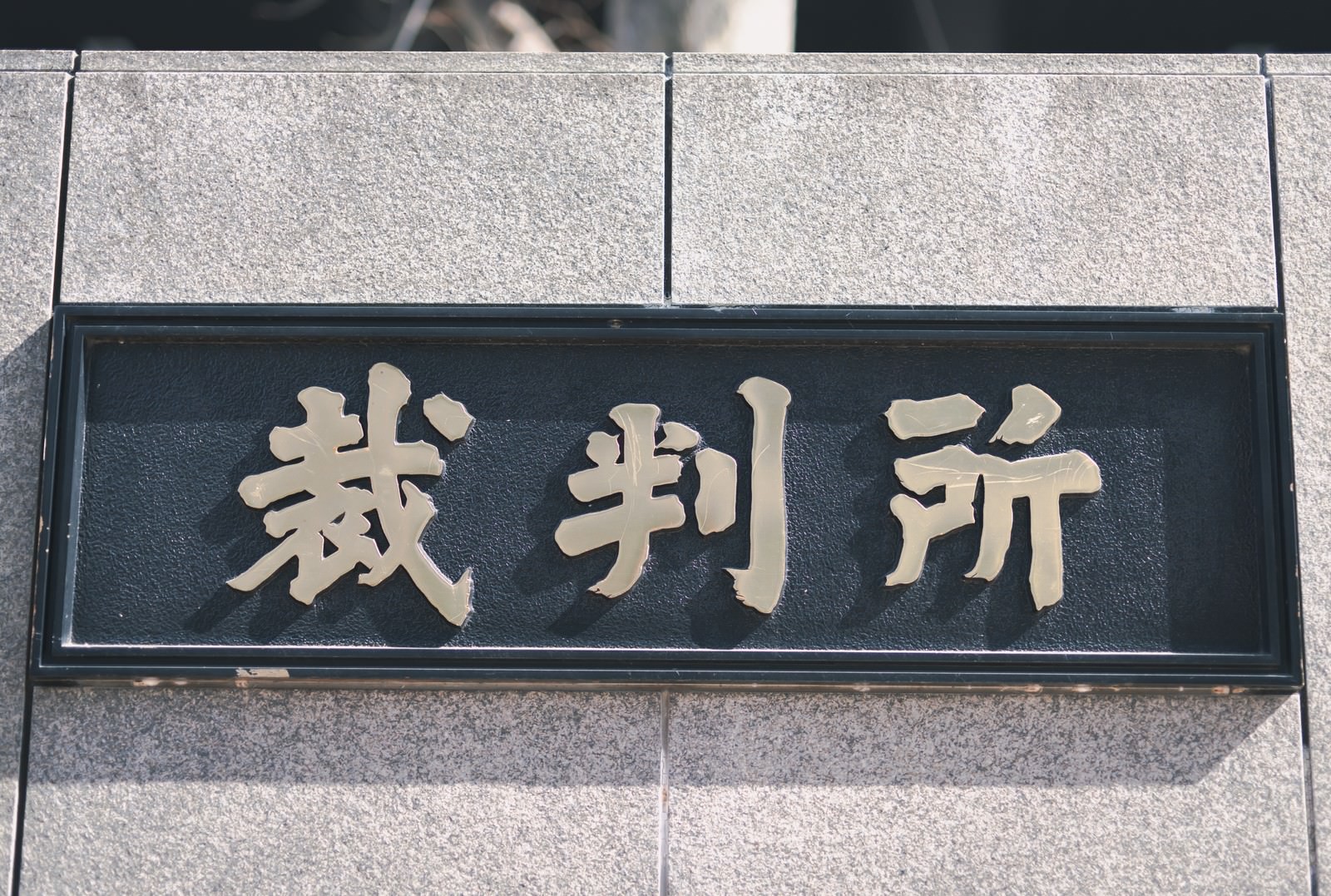 石造りの建物の壁面に設置された緑色の裁判所の看板