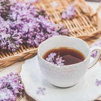 ライラックの花びら浮かぶティーカップの紅茶の写真